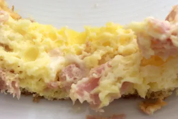 Corte de una tortilla esponjosa de jamón y queso.