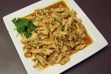 Una fuente con pollo con cilantro y lima desmenuzado.