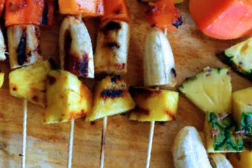 Brochetas de fruta a la parrilla sobre una tabla de madera.