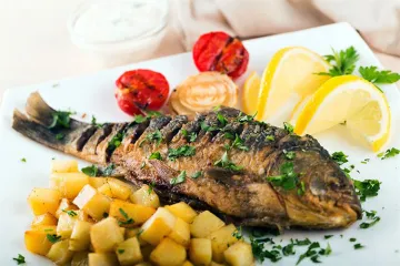 Besugo al horno con tomate, cebolla y perejil.