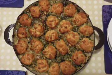Cazuela de pollo al pesto con bolas de queso y piñones recién hecha.