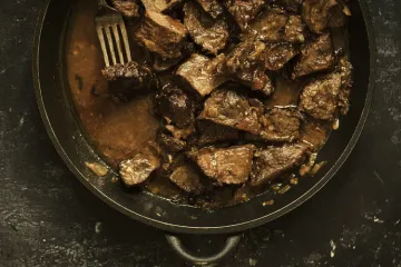 Carne guisada servida en una sartén  de hierro.