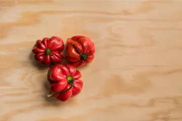 Tres chiles habaneros sobre tabla de madera.