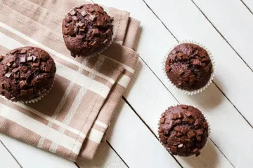 Bizcochitos de chocolate con pepitas de chocolate sobre una mesa de madera con un trapo de cocina.