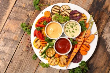 Plato de verduras a la parrilla con varias salsas.