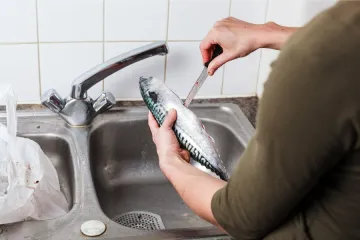 Una mujer abriendo un pescado para quitarle las tripas.