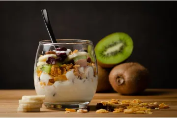 Una copa de kiwi, granola y yogur en vaso de globo.