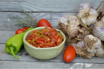 Un cuenco con piperade rodeado de algunos de los ingredientes.