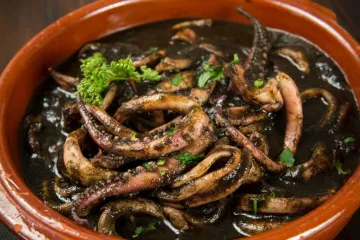 Una cazuela de barro con calamares en su tinta.