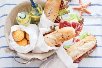 Bocadillos, comida y bebida para disfrutar de un picnic en la playa.