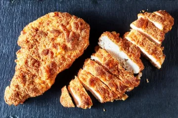 Pechugas de pollo rebozadas, una entera y una cortada.