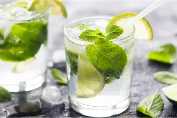 Dos vasos con mojitos, combinados con ron, azúcar, zumo de lima, menta y agua con gas.