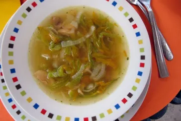 Sopa de flor de calabaza con cebolla y champiñon en un plato.