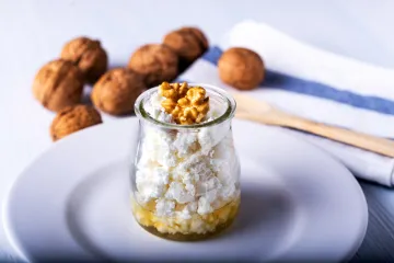 Requesón con miel decorado con nueces en un recipiente de vidrio.