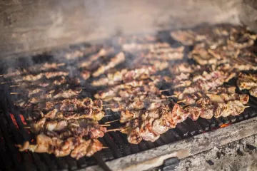 Souvlaki cocinándose en una parrilla sobre las brasas.