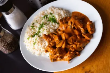 Stroganoff acompañado de arroz blanco decorado con perejil picado.