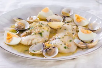 Merluza a la cosquera, o merluza koxkera, guisada con almejas.