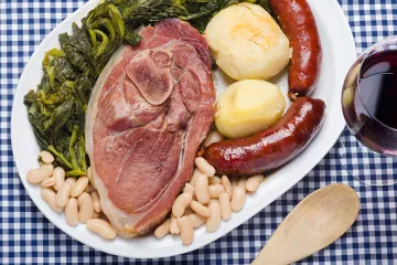 Un plato con el lacón cocido, grelos, patatas, chorizo y alubias blancas.