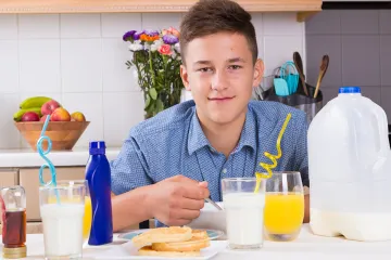 Un adolescente desayunando de forma saludable en su casa.