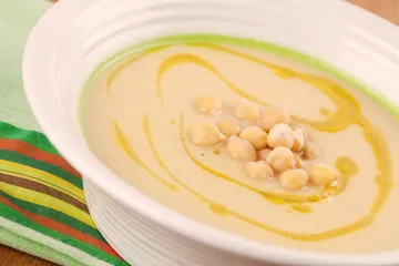 Crema especiada de garbanzos decorada con aceite de oliva y garbanzos cocidos.