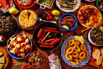 Tapas variadas, incluyendo tortilla de patata, almejas a la marinera y otras.