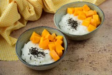 Dos cuencos con arroz con mango tailandés decorado con semillas de sésamo negro tostadas.