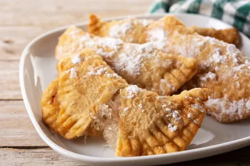 Empanadillas dulces con relleno de cabello de ángel con una empanadilla abierta, mostrando su relleno.