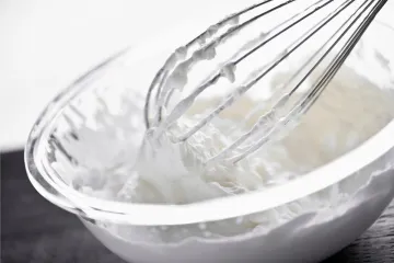 Nata montada en un bol con un batidor de varillas.