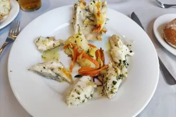 Cocochas de merluza en salsa verde decoradas con tiras de pimiento rojo asado.