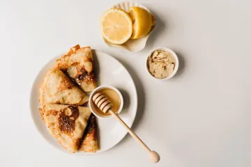 Crêpes dobladas en forma de triángulo con azúcar, miel y limón.