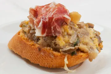 Pincho de revuelto de setas decorado con una loncha de jamón serrano.