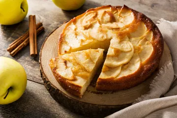 Detalle de una tarta de manzanas con u trozo ya cortado.