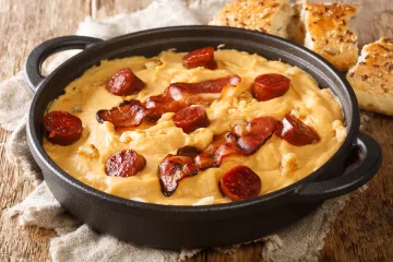 Una cazuelita de color oscuro conteniendo gachas manchegas con chorizo.