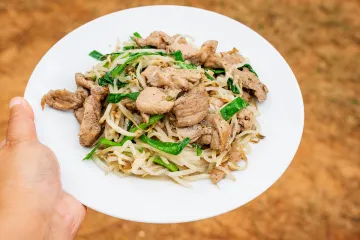 Un plato de cerdo salteado al estilo vietnamita con brotes de soja y cebollino chino.