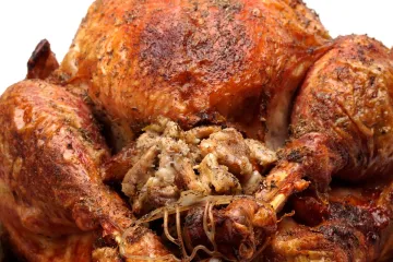 Detalle de un pavo relleno con las patas atadas con cordel y el relleno saliendo de la cavidad.