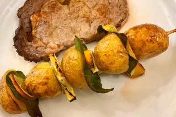 Una brocheta de patata con lima como acompañamiento de un filete a la plancha.