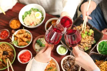 Comida china servida con vino tinto.