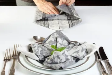 Manos doblando servilletas de forma artística.