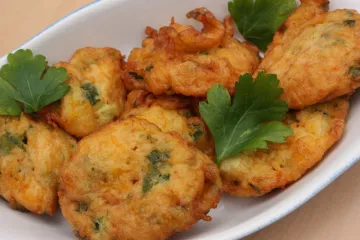 Buñuelos de calabacín bien dorados, decorados con perejil