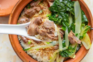Un recipiente de cerámica con arroz y trozos de pichón escabechado.