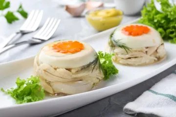 Dos áspic de ave de tamaño individual en una fuente blanca, adornados con hojas de ensalada.
