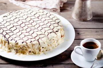 Tarta Esterhazy, un pastel húngaro de capas finas de bizcocho de nuez rellenas de crema de mantequilla y ron, cubierto con glaseado blanco decorado con dibujo de telaraña.