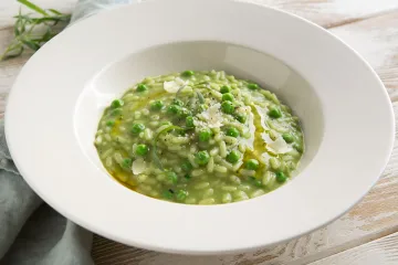 Risotto de guisantes y estragón servido en plato hondo.