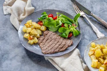 Un par de filetes al minuto con su guarnición de patatas salteadas y ensalada de tomates cherry y canónigos.