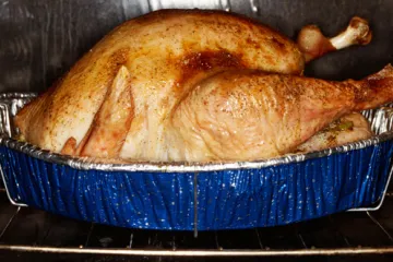 Un pavo asado en una fuente dentro del horno.