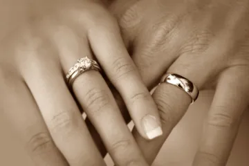 Dos manos cogidas llevando anillos de matrimonio.