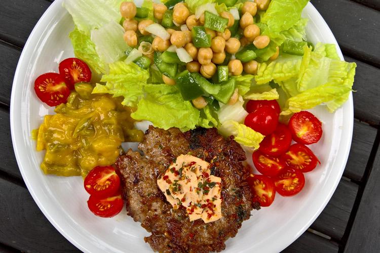 Hamburguesa de cordero con crema de queso acompañada de ensalada.
