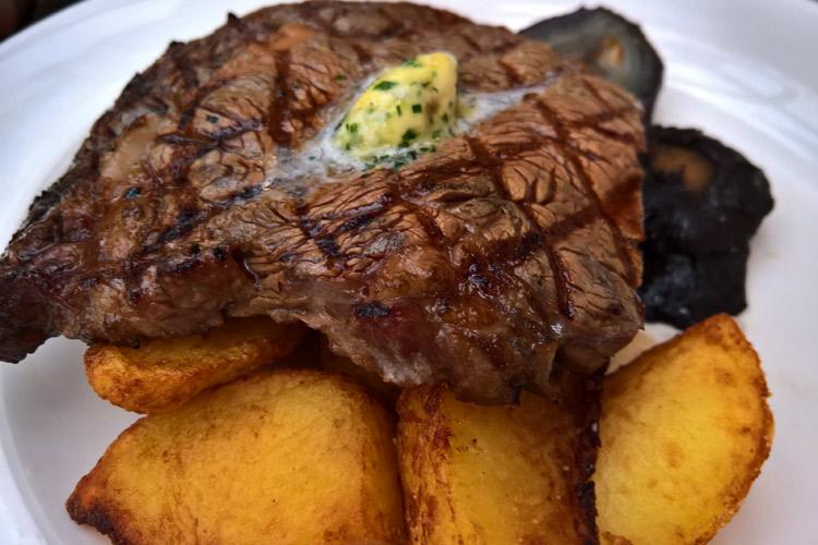 Carne a la parrilla con mantequilla condimentada, patatas y champiñones.