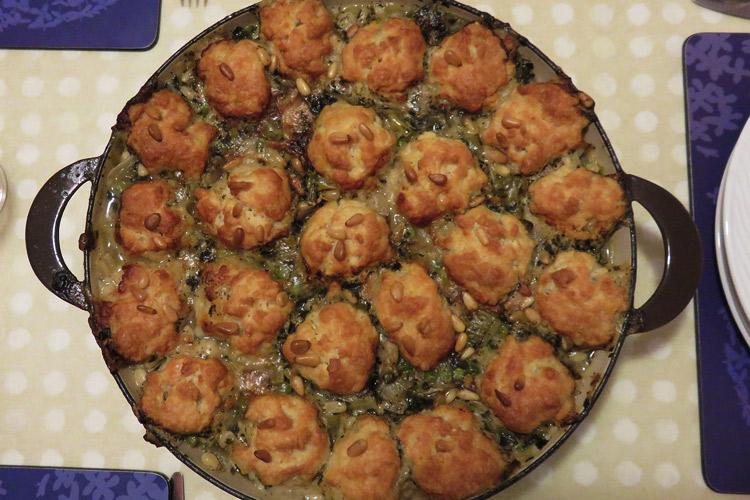 Cazuela de pollo al pesto con bolas de queso y piñones recién hecha.