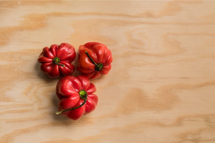 Tres chiles habaneros sobre tabla de madera.